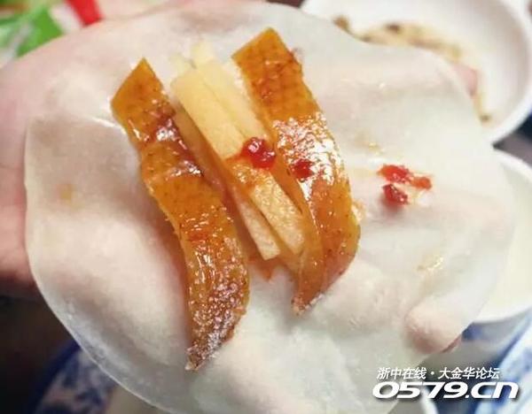 先用筷子蘸一点甜面酱抹在面皮上,夹几片烤鸭片盖在上面,再依次放入几